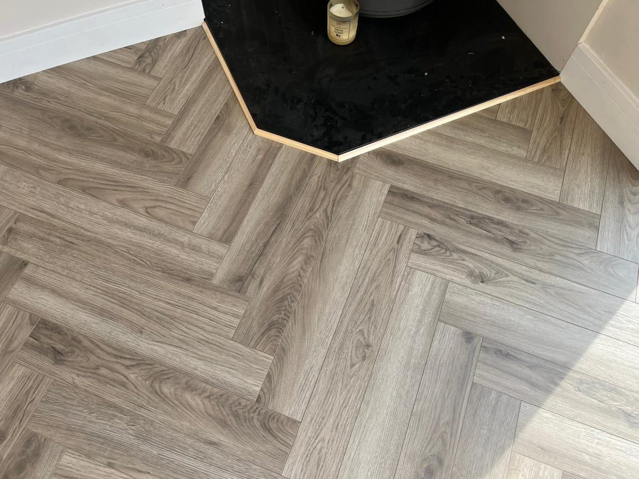 Grey herringbone floor cut neatly around a black hearth