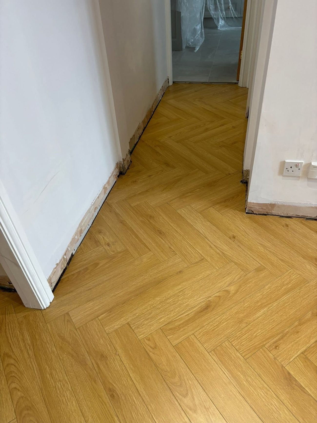 Warm oak herringbone floor running down a hall